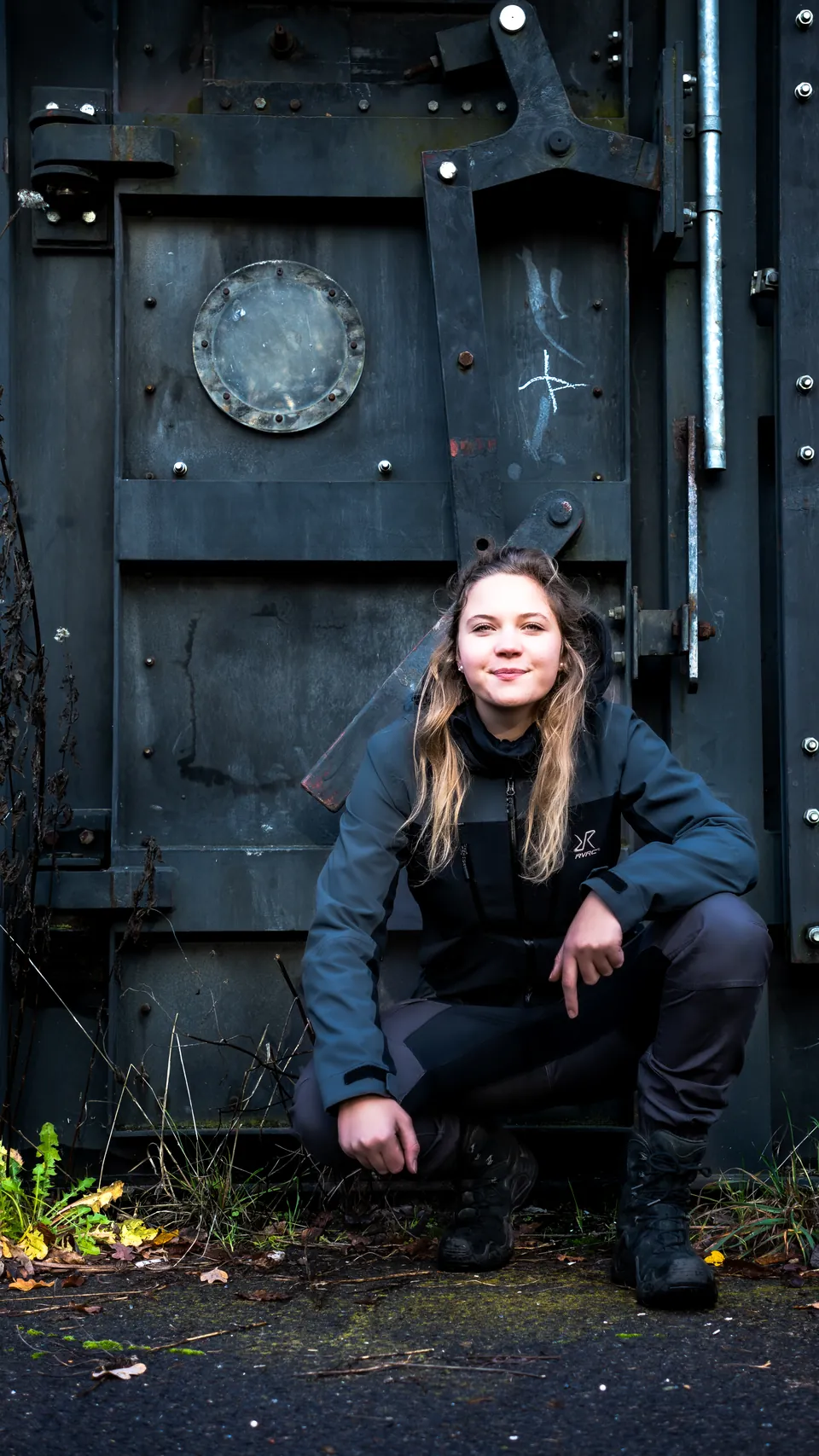 Porträt einer jungen Frau vor einer alten Stahltür im Industriepark
