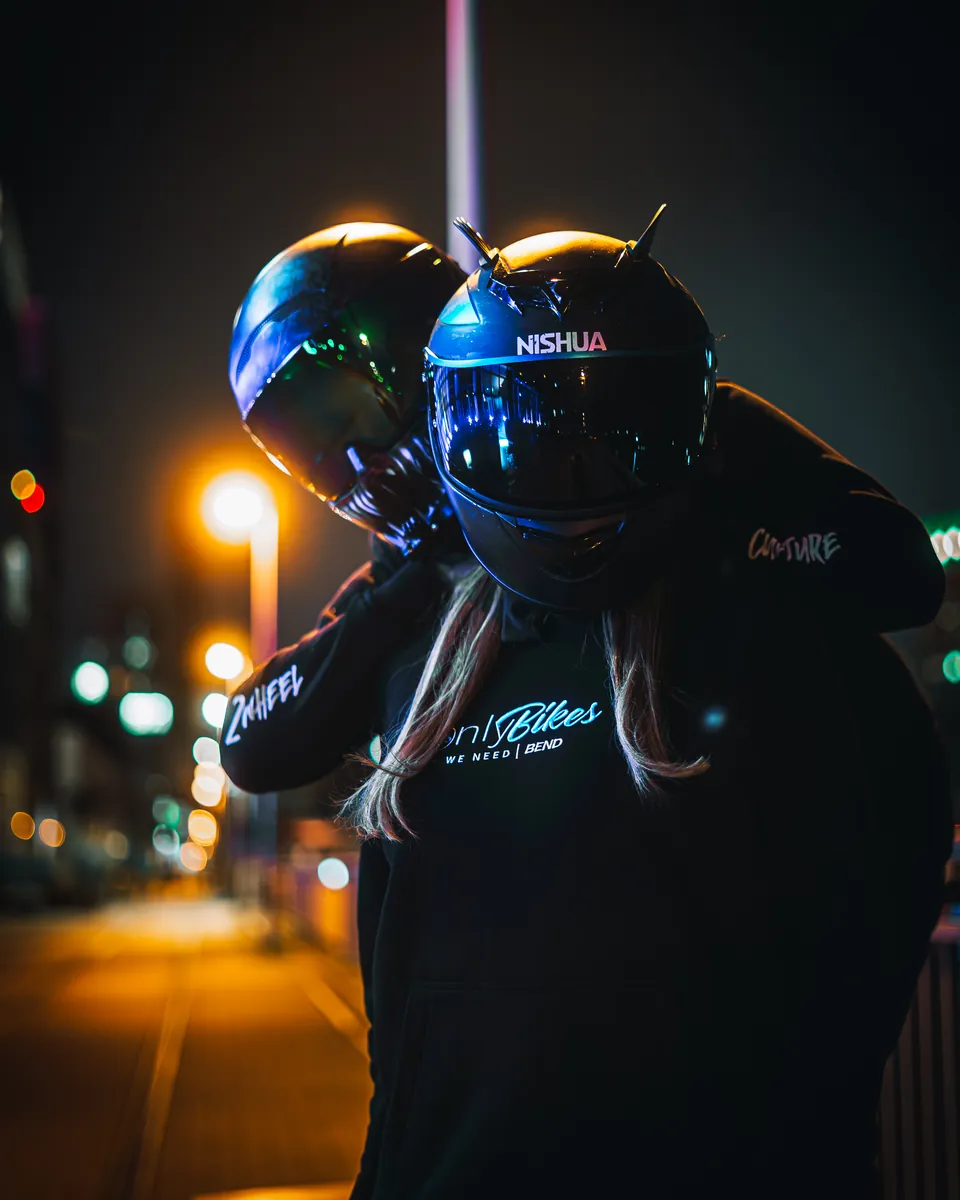 Paar mit Motorradhelmen bei Nacht in der Stadt