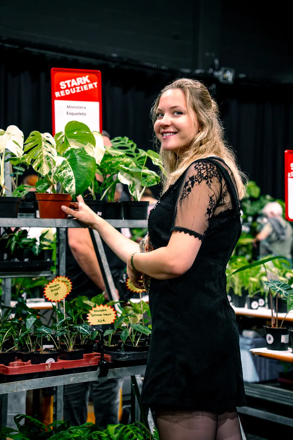Frau zwischen Zimmerpflanzen auf einem Pflanzenmarkt