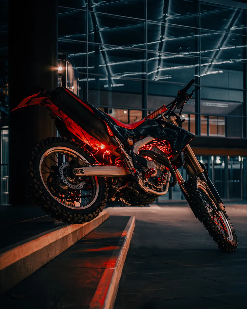 Rotes Enduro-Motorrad unter einem beleuchteten Glasdach