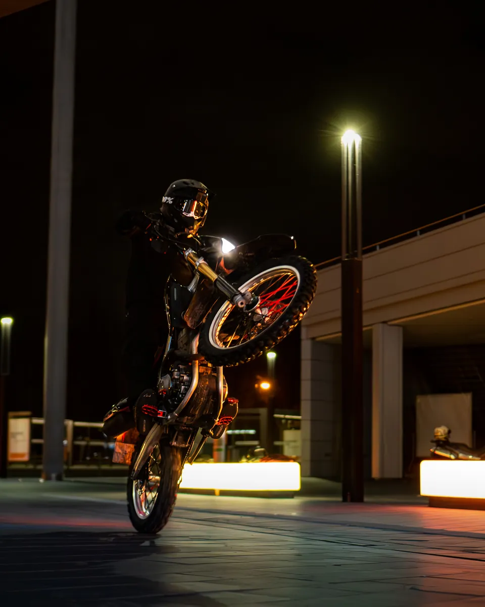 Wheelie bei Nacht auf einem beleuchteten Platz