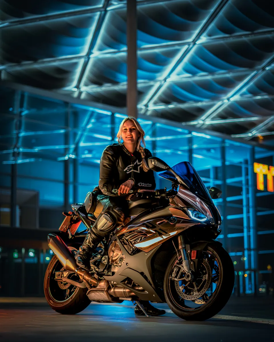 Fahrerin auf einem Superbike unter blauer Stahlkonstruktion